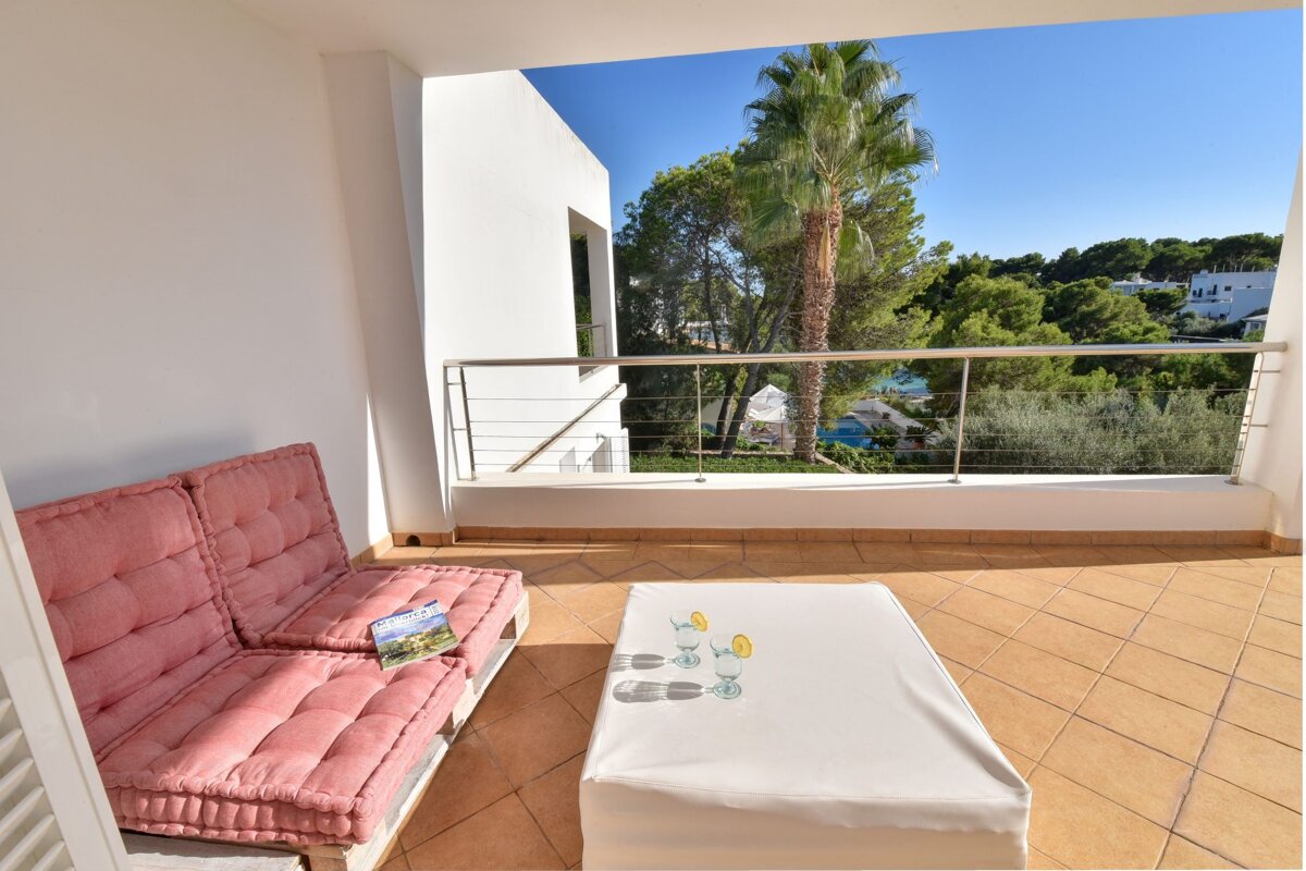 A balcony with a pink couch and a white ottoman