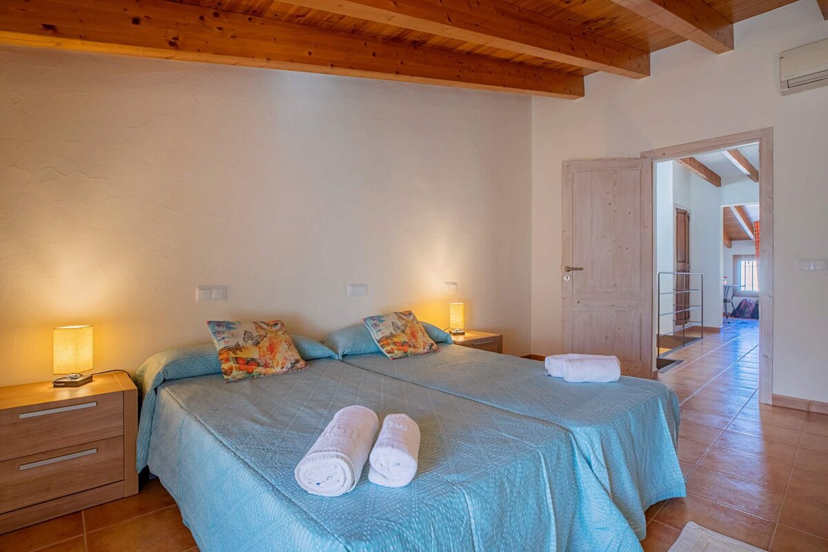 A bedroom with two beds and two lamps