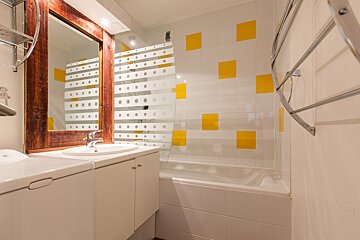 A bathroom with white tiles and yellow squares