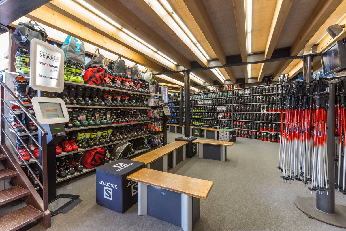 A ski shop with a check in machine and a salomon bench
