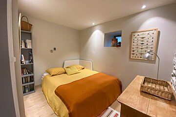 A small bedroom with a bed and a bookshelf