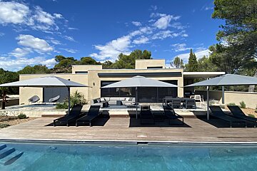 A house with a swimming pool and umbrellas in front of it