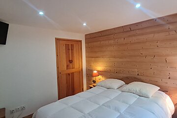 A bedroom with a wooden wall and a bed