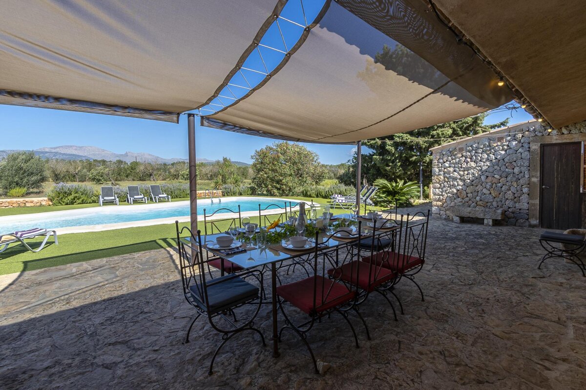A table and chairs under a canopy overlooking a swimming pool