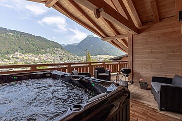 A hot tub on a balcony with mountains in the background