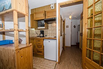 A kitchen with wooden cabinets and a small white refrigerator