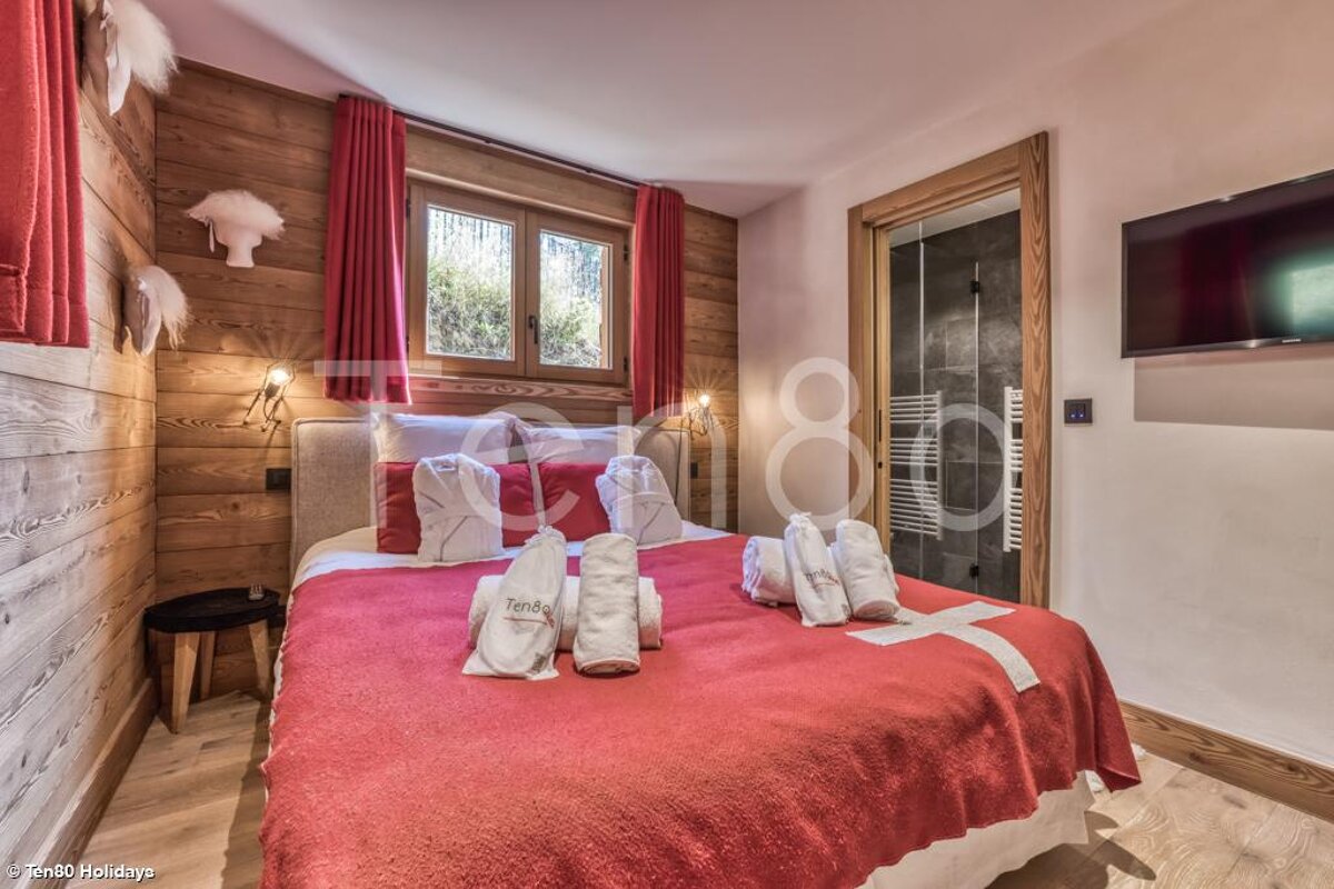 A bedroom with a large bed and a swiss flag blanket