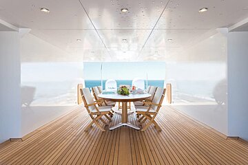 A wooden deck with a table and chairs and a view of the ocean