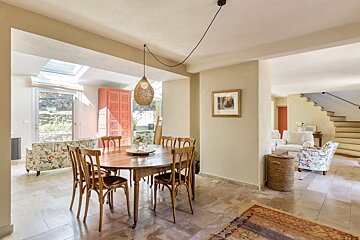 A dining room with a table and chairs and a picture on the wall