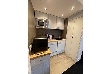 A small kitchen with white cabinets and a black microwave
