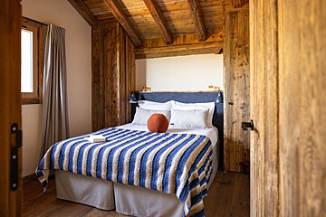 A bedroom with a blue and white striped blanket on the bed