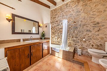 A bathroom with a stone wall and a sink and toilet