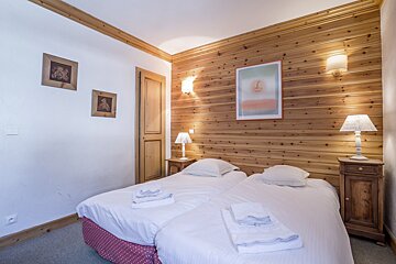 A bedroom with two beds and two lamps