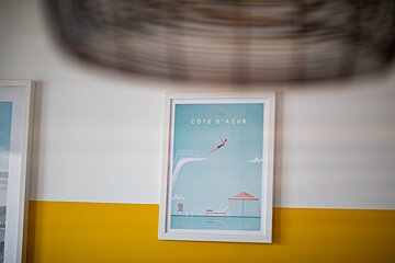 A framed picture of cote d' azur hangs on a yellow and white wall