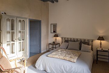 A bedroom with a bed a chair and two lamps