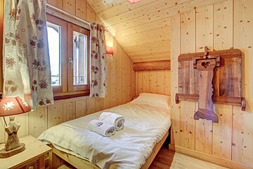 A wooden bedroom with a single bed and a lamp