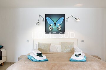 A bedroom with a blue butterfly painting above the bed