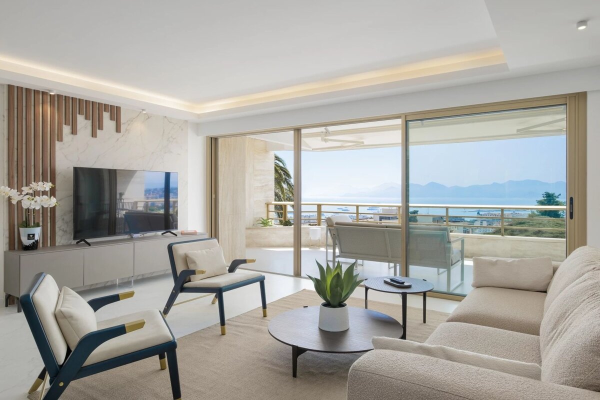 Bright, modern living room with elegant furniture, a large TV, and a balcony offering stunning panoramic sea views.