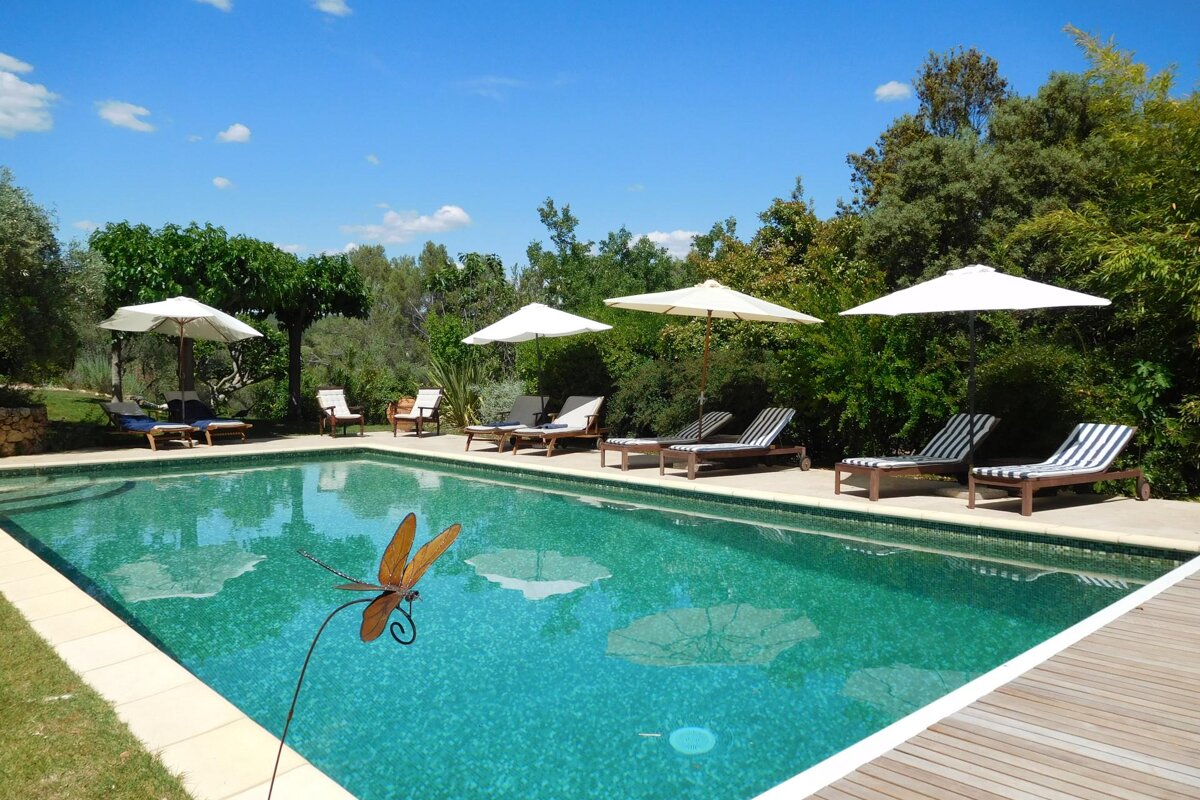 A large swimming pool surrounded by chairs and umbrellas