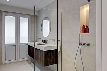 A bathroom with a walk in shower and two sinks