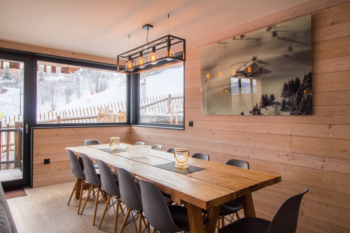 A dining room with a large wooden table and chairs