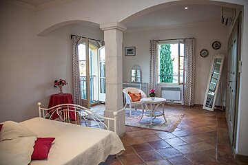 A bedroom with a bed a chair a table and a mirror