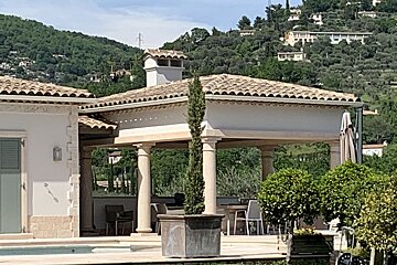A white house with a tiled roof sits next to a swimming pool