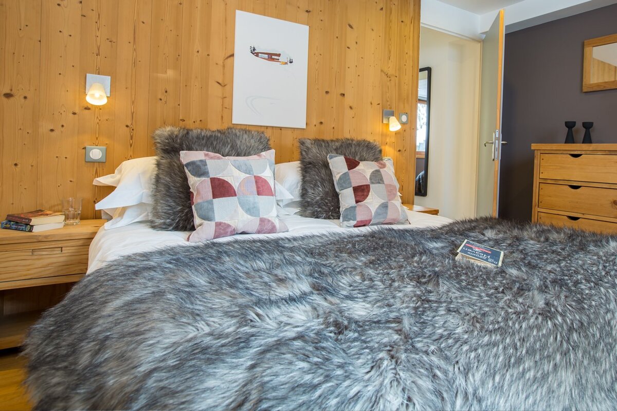 A bed with a fur blanket and pillows in a bedroom