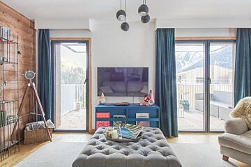 A living room with a blue ottoman and a flat screen tv