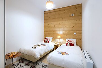 A bedroom with two beds and a wooden wall