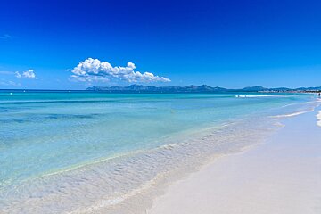 A beach with mountains in the background and a blue sky