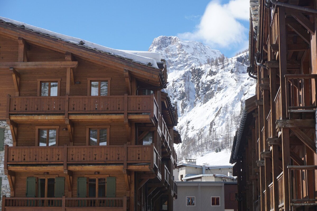 A snowy mountain is visible behind a wooden building