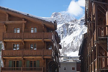 A snowy mountain is visible behind a wooden building