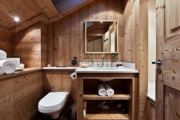 A bathroom with wood paneling and a toilet and sink