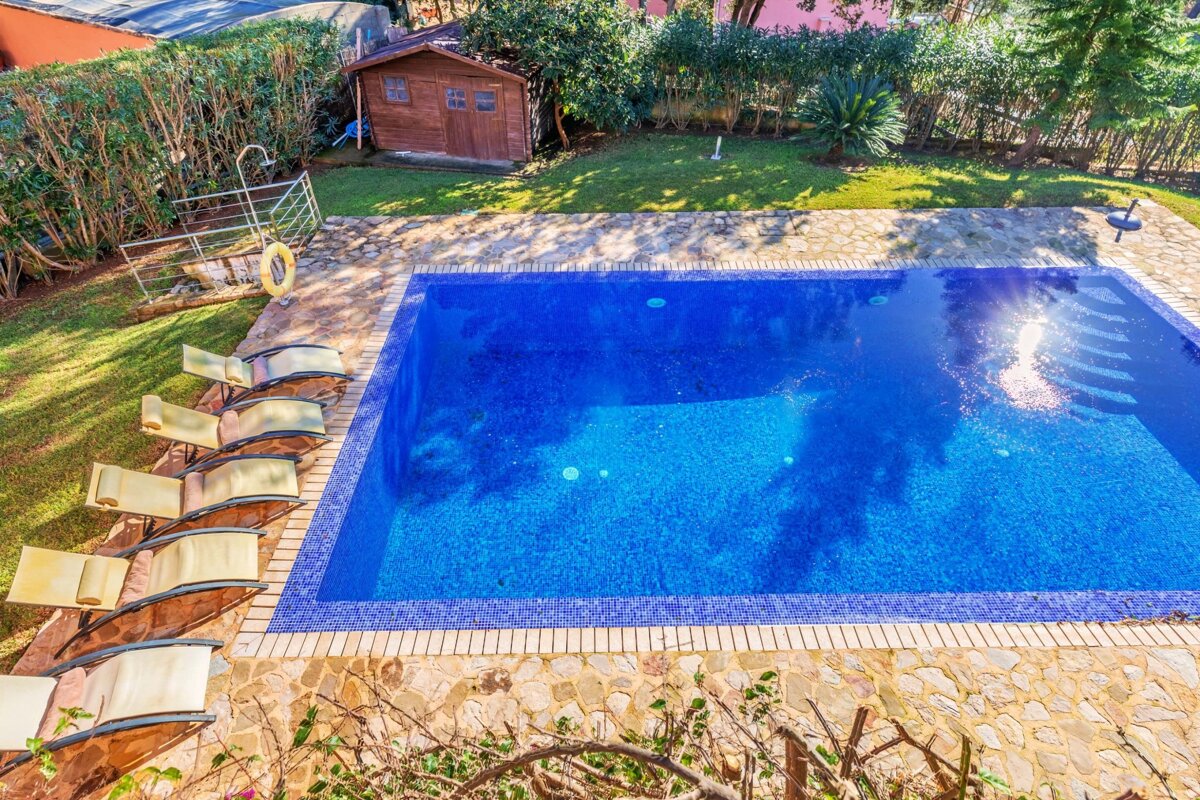 A large swimming pool surrounded by chairs and a wooden shed