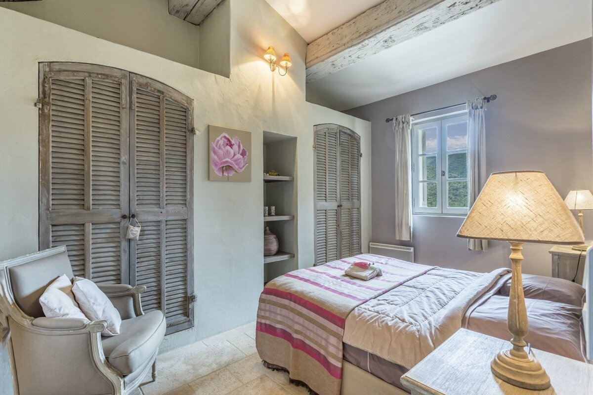 A bedroom with a bed a chair and a lamp