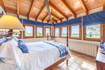 A bedroom with a canopy bed and lots of windows