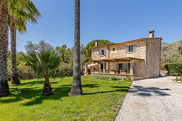 A stone house with palm trees in front of it