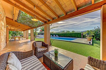 A patio with chairs and a table with a potted plant on it