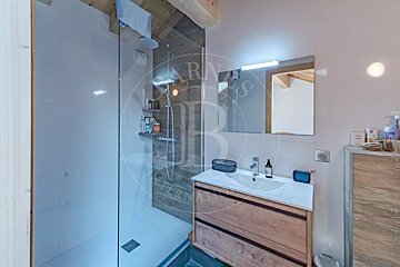 Modern bathroom featuring a glass walk-in shower, a wooden vanity with a white sink, and a rectangular mirror.