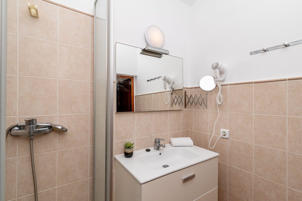 A bathroom with a sink a mirror and a hair dryer