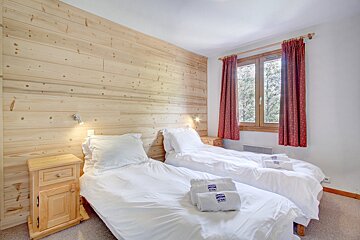 A bedroom with two beds and two towels that say tnb on them