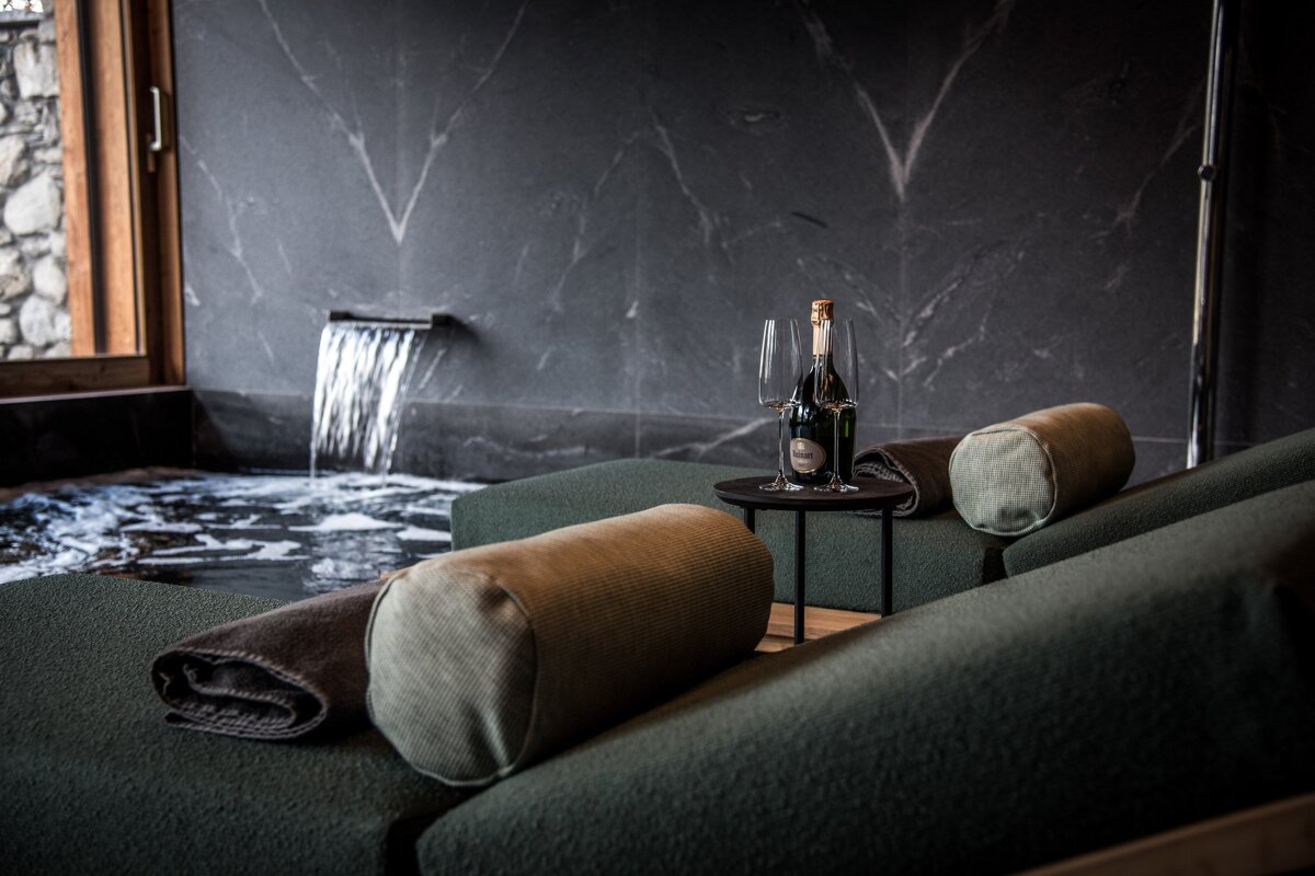 A bottle of champagne sits on a table in front of a waterfall