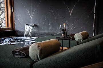A bottle of champagne sits on a table in front of a waterfall
