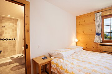 A bedroom with a bed and a small table with a book on it