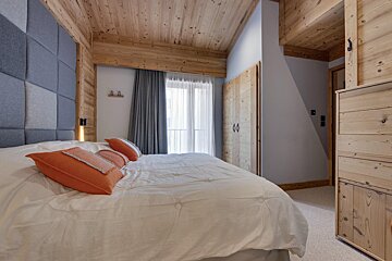 A bedroom with a wooden ceiling and a large bed