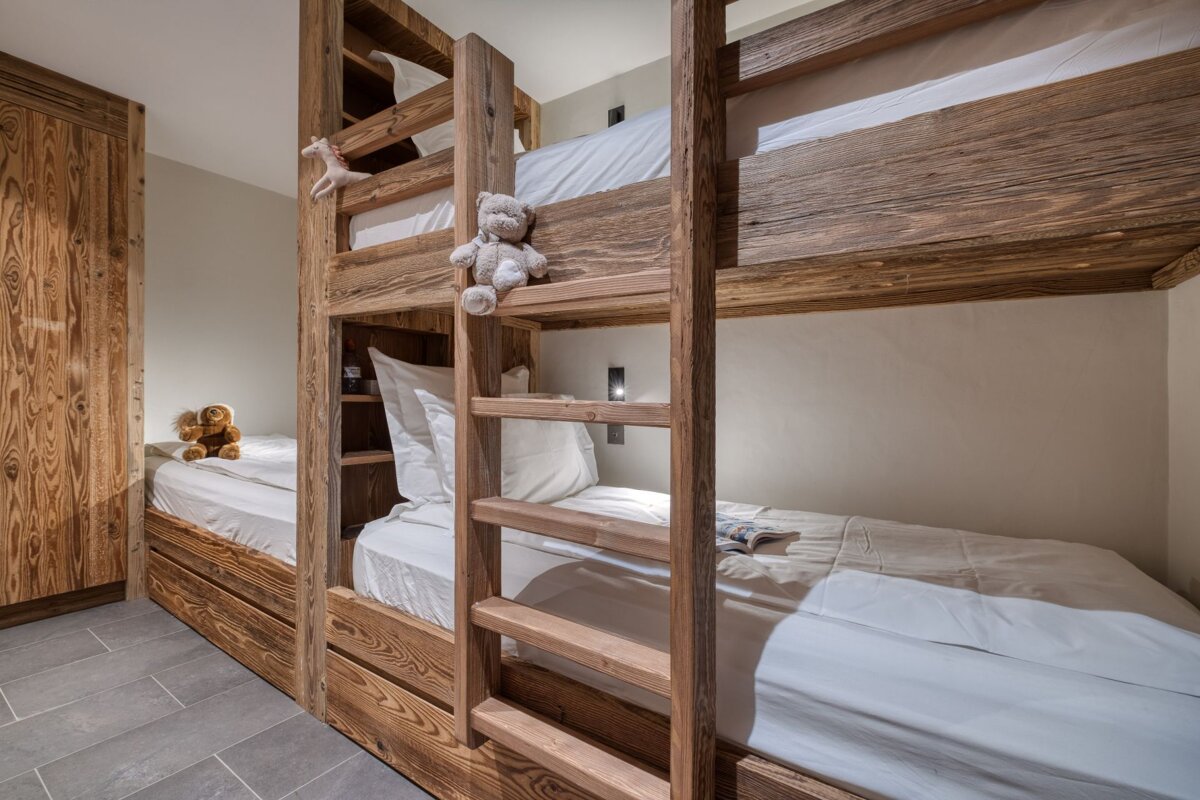 A bunk bed with a teddy bear on top of it
