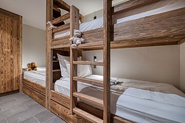A bunk bed with a teddy bear on top of it
