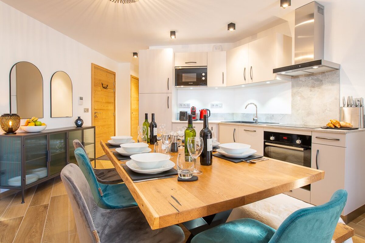 A dining room table with a bottle of wine on it