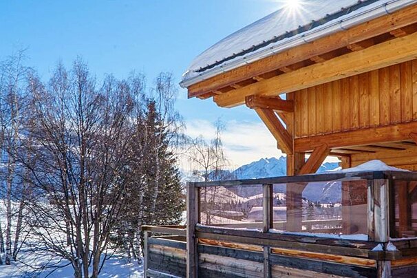 A wooden house with a balcony overlooking snowy mountains